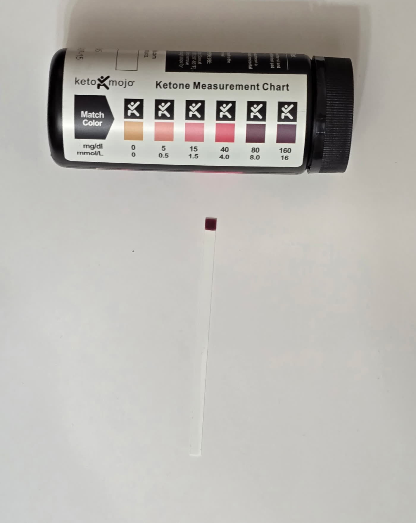Keto Mojo ketone strip on day 9 next to the color chart